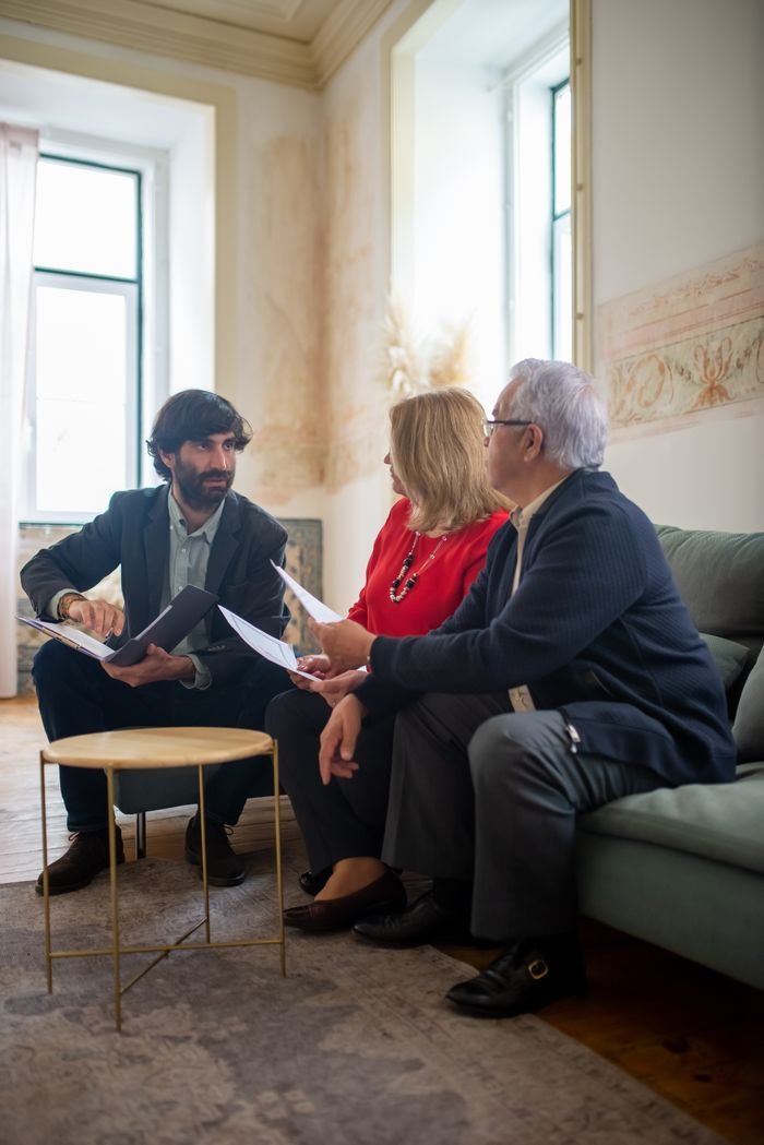 Home An advisor discussing financial documents with a senior couple indoors in a cozy living room setting.